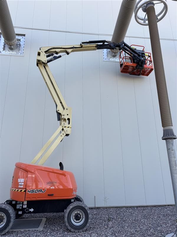 Technician in boom lift basket working on outdoor high-voltage bushings at converter station