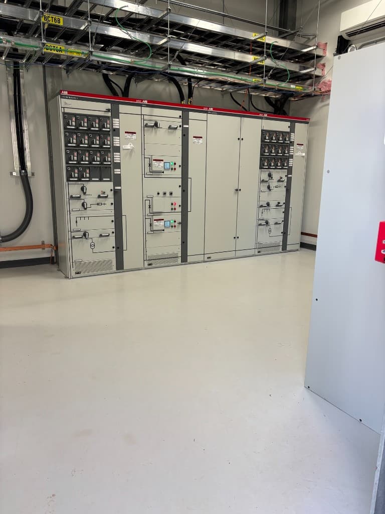 ABB switchgear and control panels with overhead cable trays in a converter station control room