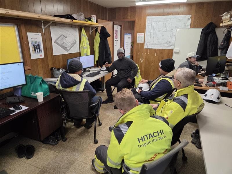Commissioning team meeting in a field office with Hitachi Energy personnel reviewing site plans